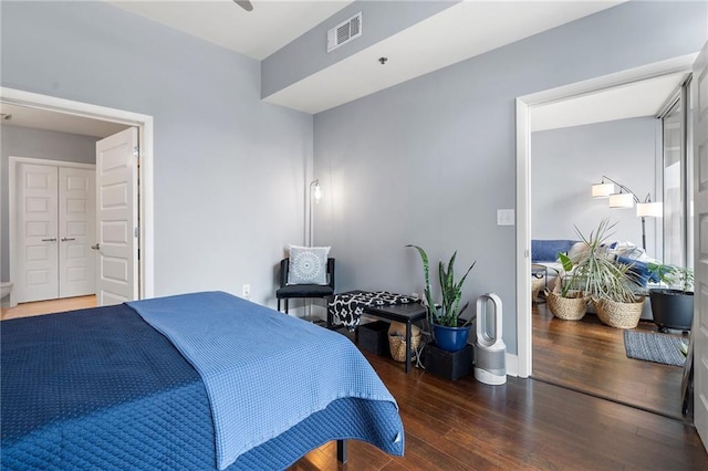 bedroom with baseboards, visible vents, and wood finished floors