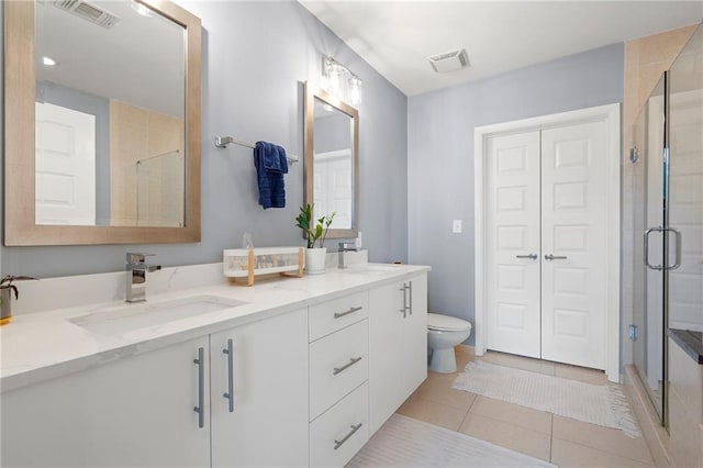 bathroom featuring tile patterned flooring, vanity, toilet, and a shower with door