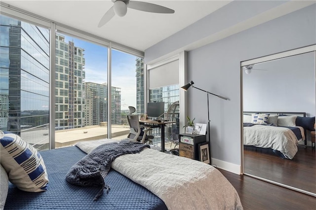 bedroom with ceiling fan, a wall of windows, wood finished floors, and baseboards