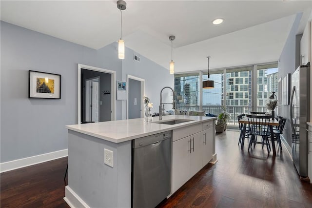 kitchen with decorative light fixtures, appliances with stainless steel finishes, sink, dark hardwood / wood-style floors, and a center island with sink