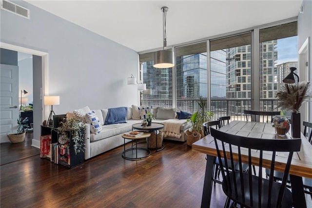 living area with a wall of windows, visible vents, and wood finished floors