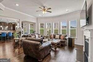 living room with ceiling fan, dark wood-type flooring, and ornamental molding