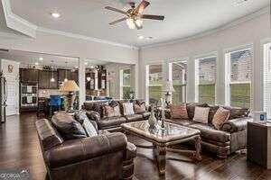 living room featuring dark hardwood / wood-style floors, ceiling fan, and ornamental molding