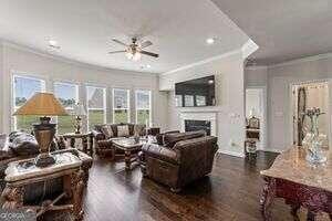 living room featuring dark hardwood / wood-style floors, plenty of natural light, crown molding, and ceiling fan