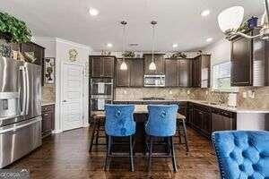 kitchen with decorative backsplash, dark brown cabinetry, stainless steel appliances, a kitchen island, and hanging light fixtures