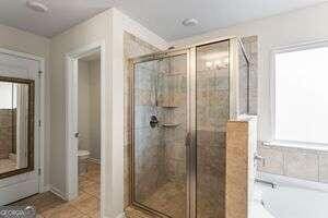 bathroom featuring tile patterned flooring, toilet, and plus walk in shower