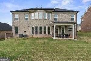 rear view of property featuring a patio area, a yard, and central air condition unit