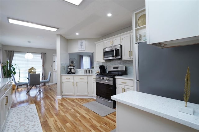 kitchen featuring white cabinetry, stainless steel appliances, light hardwood / wood-style floors, decorative backsplash, and decorative light fixtures