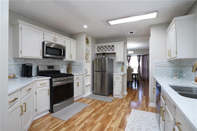 kitchen featuring sink, appliances with stainless steel finishes, white cabinetry, tasteful backsplash, and light wood-type flooring