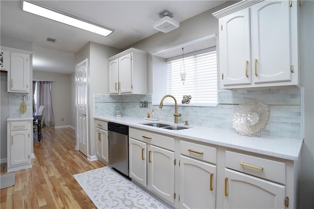 kitchen featuring sink, white cabinets, hanging light fixtures, stainless steel dishwasher, and light hardwood / wood-style flooring