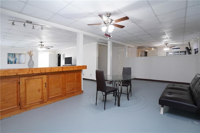 dining area featuring a paneled ceiling, concrete floors, and ceiling fan