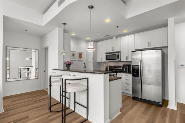 855 Peachtree St NE Unit 2706, Atlanta, GA 30308 - kitchen featuring light wood-style floors, visible vents, appliances with stainless steel finishes, dark countertops, and a breakfast bar area
