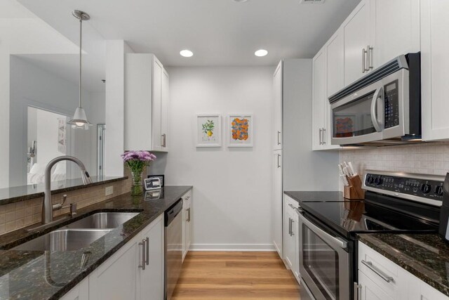 855 Peachtree St NE Unit 2706, Atlanta, GA 30308 - kitchen featuring light wood-type flooring, backsplash, stainless steel appliances, pendant lighting, and a sink