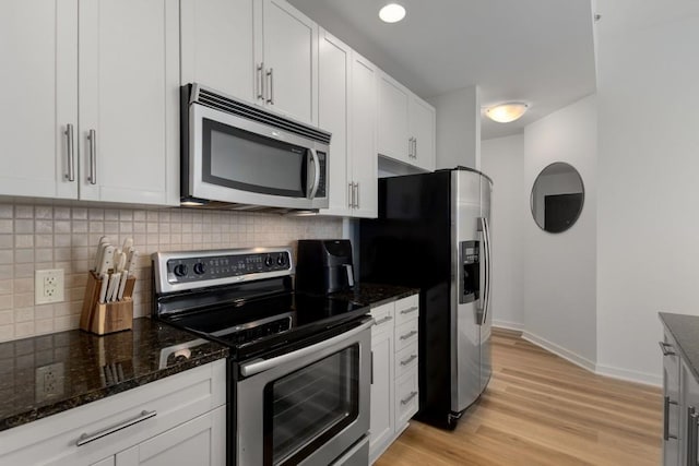 855 Peachtree St NE Unit 2706, Atlanta, GA 30308 - kitchen with dark stone countertops, light wood-style flooring, white cabinetry, decorative backsplash, and appliances with stainless steel finishes