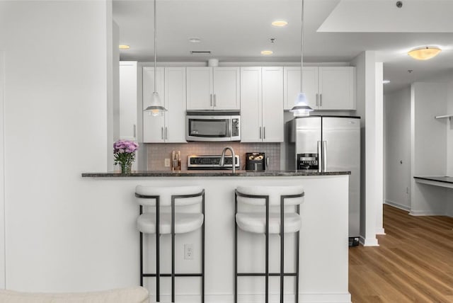 855 Peachtree St NE Unit 2706, Atlanta, GA 30308 - kitchen featuring backsplash, wood finished floors, a kitchen bar, and stainless steel appliances