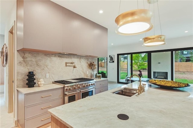 kitchen with sink, light stone counters, pendant lighting, a healthy amount of sunlight, and range with two ovens