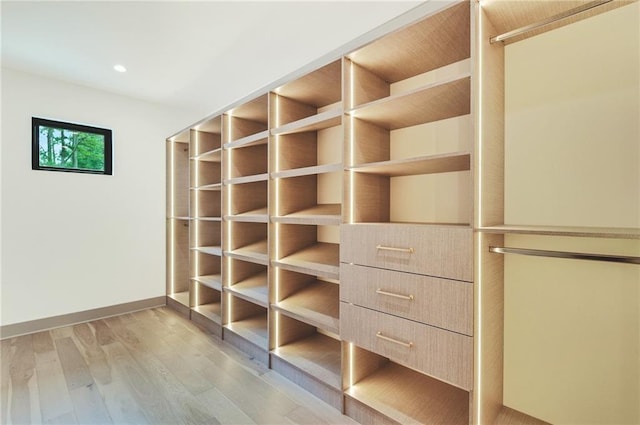 walk in closet with light hardwood / wood-style floors