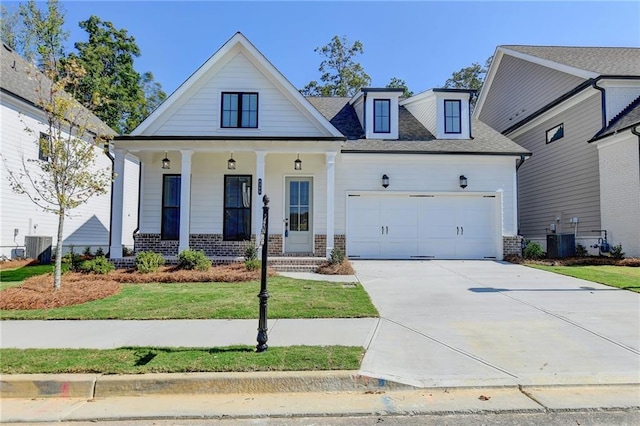 view of front of property featuring a front lawn, central air condition unit, concrete driveway, covered porch, and a garage