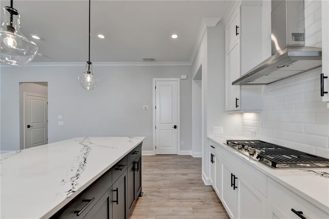 kitchen featuring wall chimney range hood, tasteful backsplash, stainless steel gas cooktop, ornamental molding, and visible vents