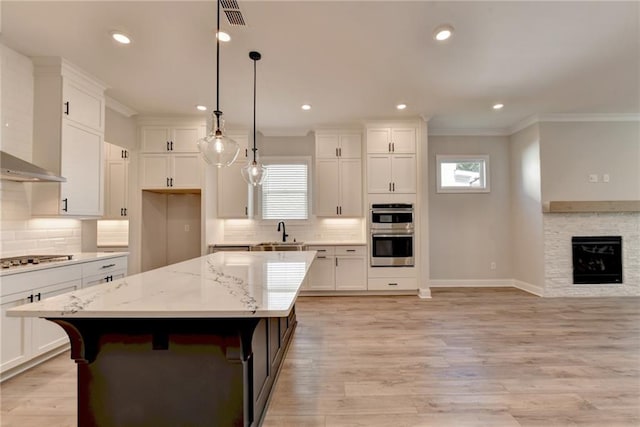 kitchen with cooktop, stainless steel double oven, visible vents, ornamental molding, and a sink