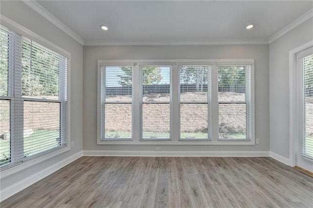 spare room with baseboards, wood finished floors, and crown molding