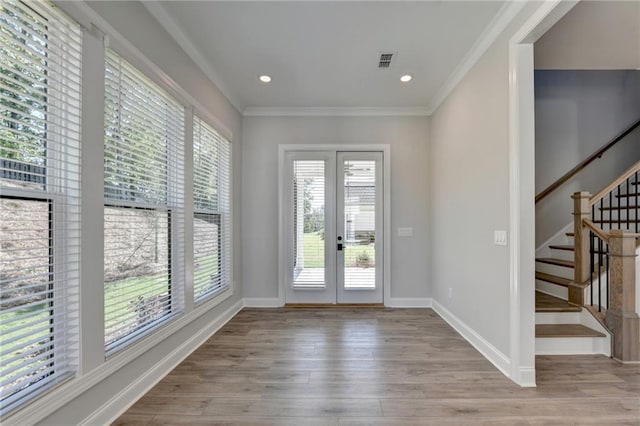 foyer featuring wood finished floors, visible vents, baseboards, and ornamental molding