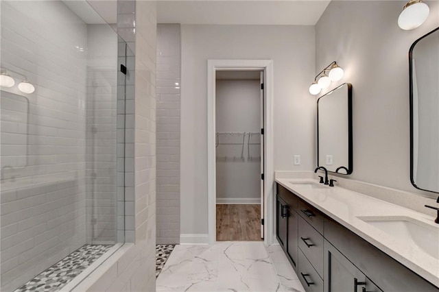 bathroom featuring marble finish floor, walk in shower, and a sink