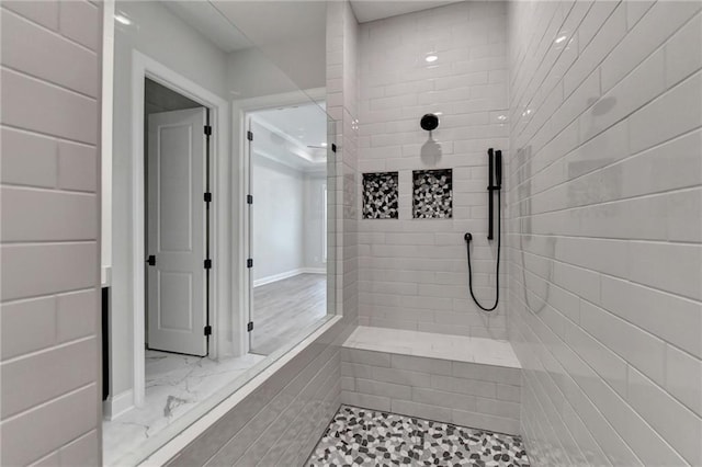 full bath with a tile shower and marble finish floor