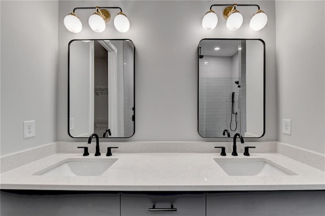 full bathroom featuring a sink, double vanity, and a tile shower