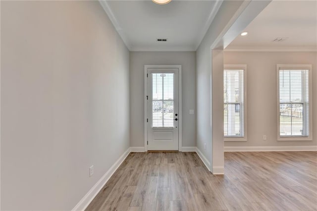 doorway with baseboards, ornamental molding, visible vents, and light wood-style flooring