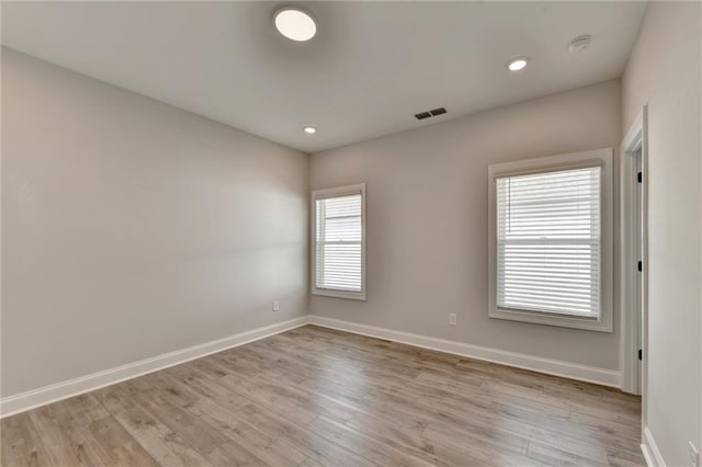 empty room featuring baseboards, light wood-style flooring, visible vents, and recessed lighting