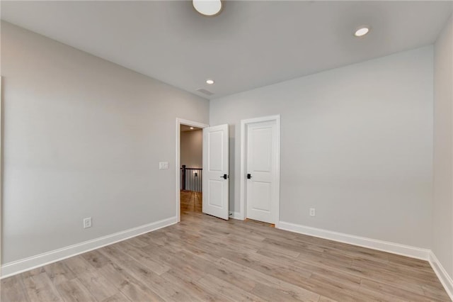 empty room featuring light wood-type flooring, baseboards, recessed lighting, and visible vents