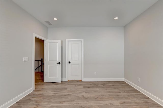 empty room with light wood finished floors, baseboards, visible vents, and recessed lighting