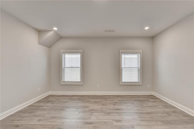 empty room featuring plenty of natural light, baseboards, and light wood-style flooring