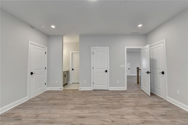unfurnished bedroom with recessed lighting, light wood-style flooring, ensuite bath, and baseboards
