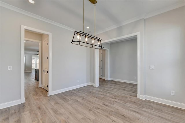 unfurnished dining area featuring baseboards, crown molding, and light wood finished floors