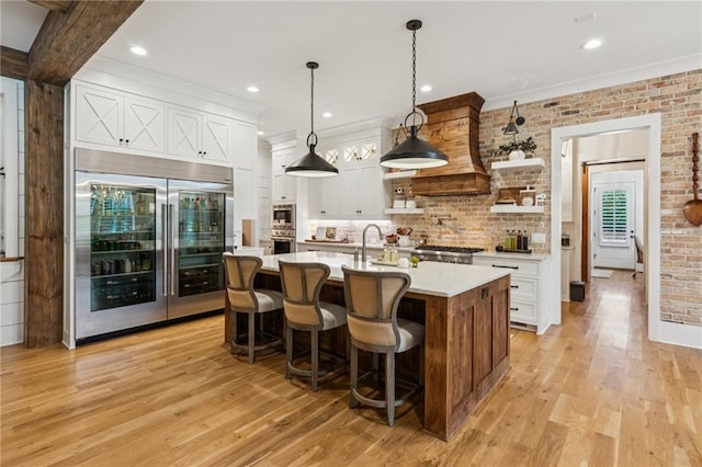 150 Trinity Farm Dr, Canton, GA 30115 - kitchen with built in appliances, light countertops, white cabinetry, light wood-style floors, and a kitchen island with sink