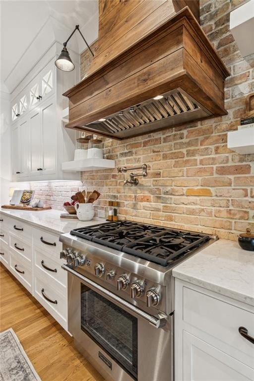 150 Trinity Farm Dr, Canton, GA 30115 - kitchen featuring stainless steel range, wall chimney range hood, white cabinetry, light stone countertops, and light wood-style floors
