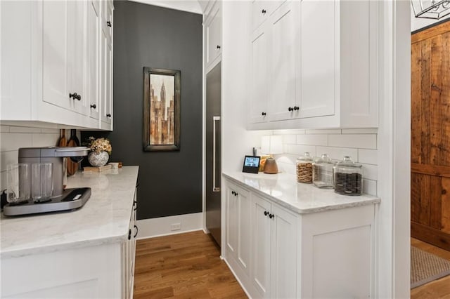 150 Trinity Farm Dr, Canton, GA 30115 - kitchen with light wood-type flooring, backsplash, white cabinetry, and light stone counters