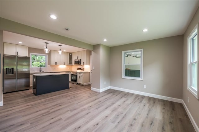 5961 John St, Austell, GA 30106 - kitchen with appliances with stainless steel finishes, a kitchen island, light wood-type flooring, light countertops, and tasteful backsplash