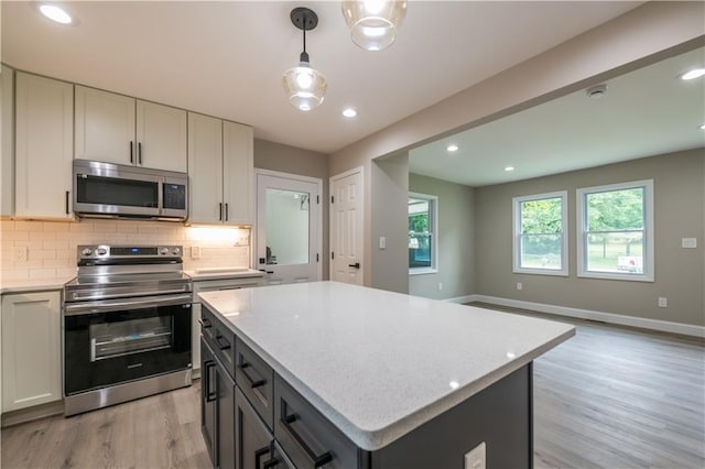5961 John St, Austell, GA 30106 - kitchen featuring appliances with stainless steel finishes, light wood-style flooring, decorative backsplash, a kitchen island, and pendant lighting