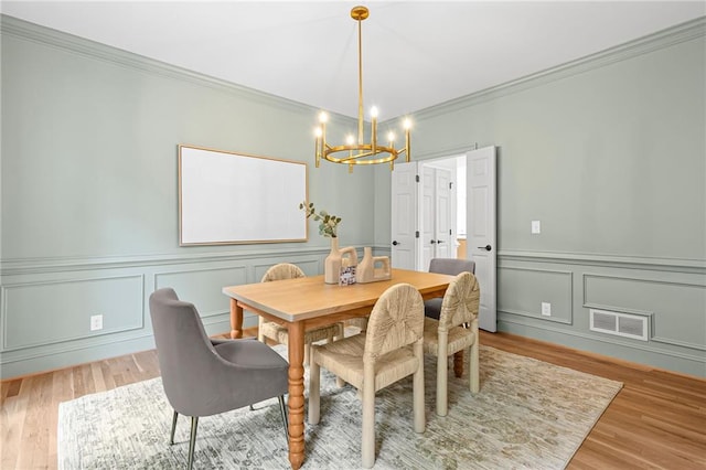 1017 Mill Creek Mnr NE, Brookhaven, GA 30319 - dining room featuring a chandelier, crown molding, light wood-style floors, a decorative wall, and wainscoting