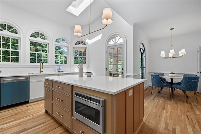 1017 Mill Creek Mnr NE, Brookhaven, GA 30319 - kitchen with dishwasher, stainless steel microwave, a skylight, a chandelier, and light wood-style flooring