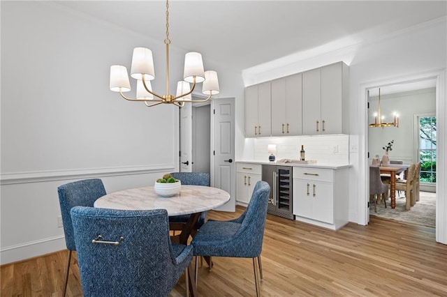 1017 Mill Creek Mnr NE, Brookhaven, GA 30319 - dining space featuring a chandelier, wine cooler, light wood-type flooring, crown molding, and a bar