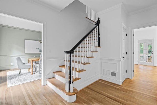 1017 Mill Creek Mnr NE, Brookhaven, GA 30319 - stairs featuring ornamental molding, wood finished floors, a decorative wall, and a wainscoted wall