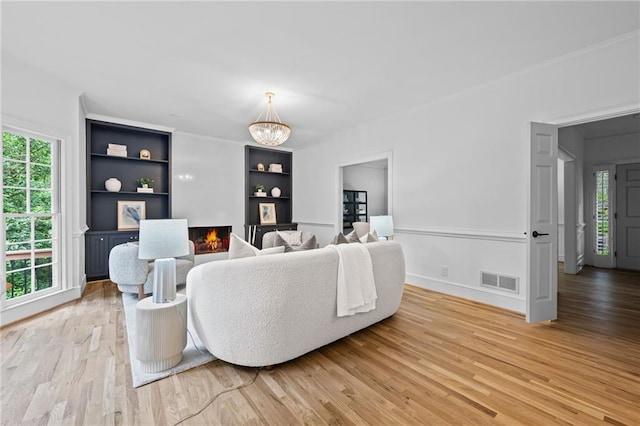 1017 Mill Creek Mnr NE, Brookhaven, GA 30319 - living room featuring plenty of natural light, a chandelier, light wood finished floors, and a lit fireplace