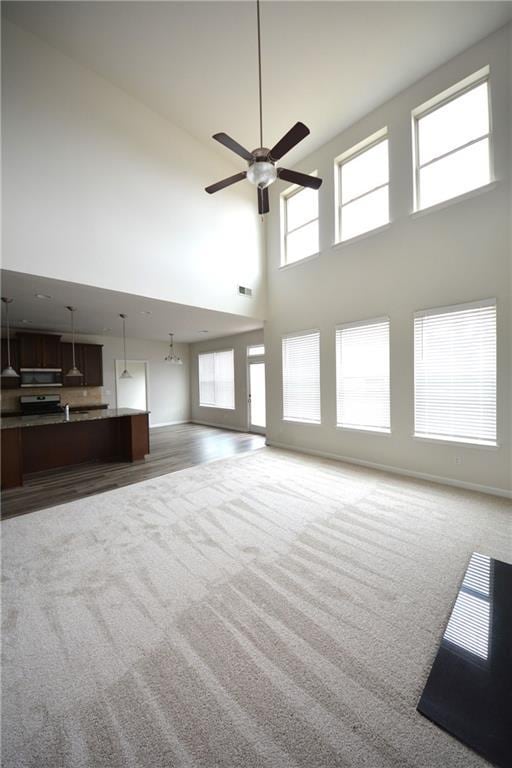 unfurnished living room with visible vents, baseboards, ceiling fan, and carpet flooring