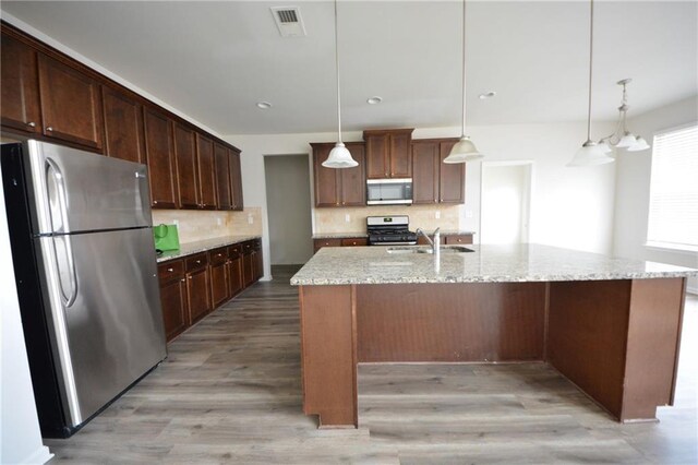 kitchen with visible vents, a sink, stainless steel appliances, light wood-style floors, and tasteful backsplash