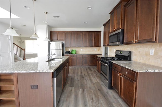 kitchen with a sink, stainless steel appliances, light wood-style floors, and decorative backsplash