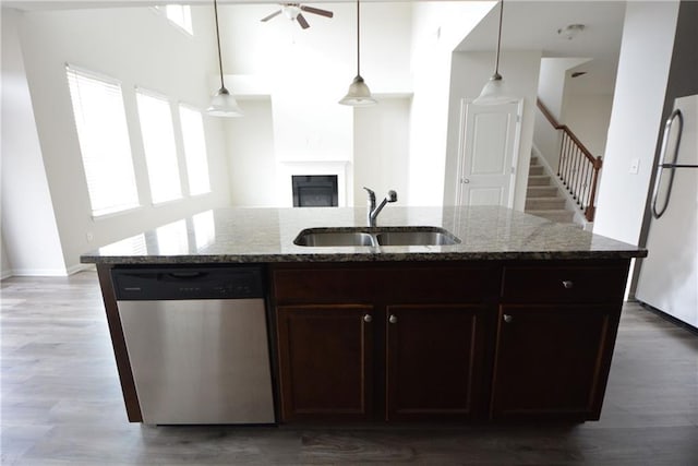 kitchen with a sink, a glass covered fireplace, light stone counters, and stainless steel appliances